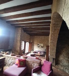 uma sala de estar com mobiliário roxo e uma parede de pedra em Ca l'Aleixa Rooms em Bisbal de Falset
