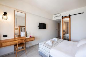a bedroom with a bed and a desk and a mirror at Pedi Beach Hotel in Symi