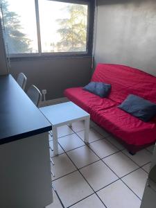 Zimmer mit einem roten Sofa und einem Tisch in der Unterkunft Studio Cozy 245 in La Mulatière