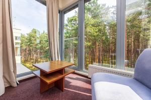 a room with a couch and a table and large windows at Meduza Hotel in Palanga