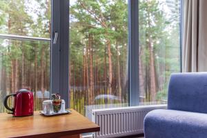 Ein Tisch mit einem Teekessel darauf neben einem Fenster in der Unterkunft Meduza Hotel in Palanga