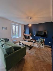 uma sala de estar com um sofá e uma televisão de ecrã plano em Magnifique maison au cœur d'un jardin paysager em Breuillet
