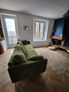 un sofá verde en una sala de estar con 2 ventanas en Magnifique maison au cœur d'un jardin paysager, en Breuillet