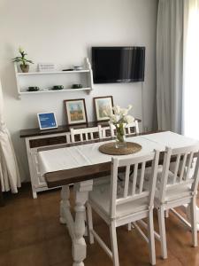 ein weißer Esstisch mit weißen Stühlen und einem Fernseher in der Unterkunft PRIMERA LINEA PEÑISMAR in Peñíscola