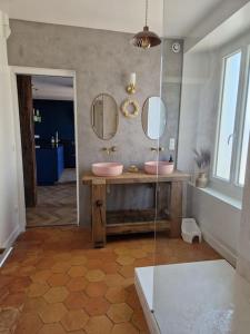 a bathroom with two sinks and two mirrors at Magnifique maison au cœur d'un jardin paysager in Breuillet