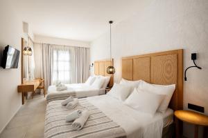 2 Betten in einem Hotelzimmer mit Handtüchern darauf in der Unterkunft Pedi Beach Hotel in Symi