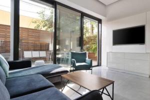 een woonkamer met een bank en stoelen en een tv bij Garden Oasis by Five Stay in Tel Aviv