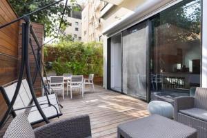 een terras met stoelen en tafels en een balkon bij Garden Oasis by Five Stay in Tel Aviv