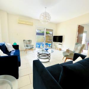a living room with a blue couch and chairs at Mediterranean Breeze Villa in Protaras