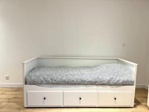 ein weißes Bett mit einer grauen Decke drauf in der Unterkunft *Marquer* Studio proche gare M23 in Annemasse
