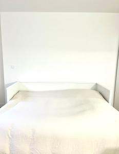 ein leeres weißes Bett in einem weißen Schlafzimmer in der Unterkunft *Marquer* Studio proche gare M23 in Annemasse