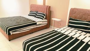 two beds sitting next to each other in a room at Kulai Apartment 5BR11Pax near IOI, Aeon and Senai Airport in Kulai
