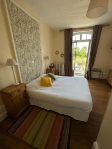 ein Schlafzimmer mit einem Bett mit gelbem Kissen darauf in der Unterkunft Hôtel les Grands Chênes in Saint-Fargeau