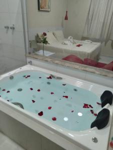 uma banheira com flores e um espelho em Pousada Cardoso em Ipiaú