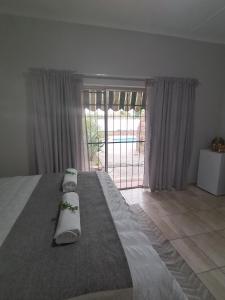 a bedroom with a large bed and a large window at Oppi Draai Guesthouse in Oudtshoorn
