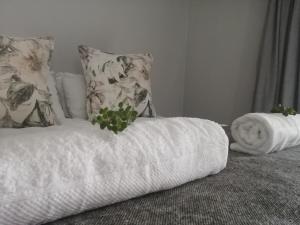 Oppi Draai Guesthouse في أوتشورن: سرير ابيض عليه منشفة وزرع