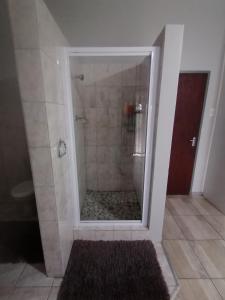 a shower with a glass door in a bathroom at Oppi Draai Guesthouse in Oudtshoorn