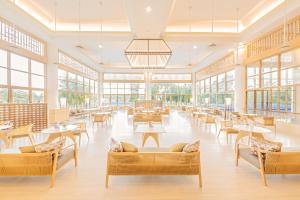 een cafetaria met tafels, stoelen en ramen bij Glenmarie Hotel and Golf Resort in Shah Alam