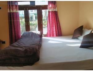 a bedroom with a large bed with red curtains at Morning Calm Homestay, Joshimath in Joshīmath