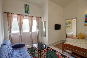 sala de estar con sofá azul y ventana en Calangute Cosy 1 bhk Apartment en Calangute