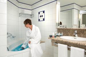 a woman standing in a bathroom with a tub at Vichy Célestins Spa Hôtel in Vichy