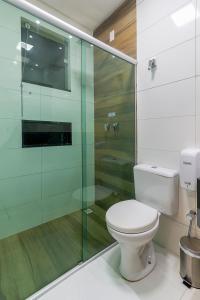 uma casa de banho com um WC e uma cabina de duche em vidro. em Hotel Pousada Tribalista em Arraial d'Ajuda