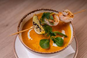 a bowl of soup with shrimp and greens on top at Holiday Inn Krakow City Centre by IHG in Krakow