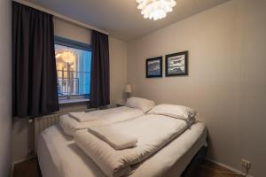 a bedroom with a bed with white sheets and a window at Day Dream Hafnarstræti Main Street One Bedroom in Akureyri