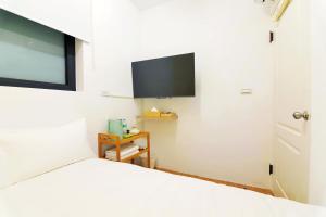 a bedroom with a bed and a flat screen tv at 木直海安 貳館 MuZe 2 in Tainan