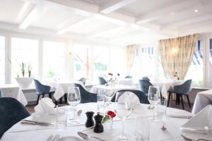 un comedor con mesas y sillas blancas y ventanas en Hotel Gruber, en Steinheim