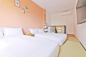 two beds in a hotel room with white sheets at 木直海安 貳館 MuZe 2 in Tainan