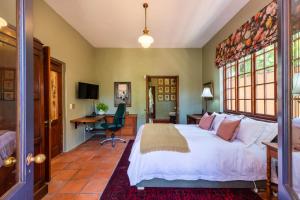 a bedroom with a large white bed and a desk at Kensington Views in Cape Town