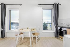 uma cozinha branca com uma mesa e duas janelas em Apartment in Prague N1 em Praga