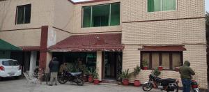 zwei Männer, die vor einem Gebäude stehen und draußen Motorräder parken in der Unterkunft Hotel New Star in Multan