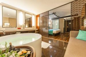 a bathroom with a bath tub and a bedroom at SSAW Boutique Hotel Hefei Intime Centre in Hefei