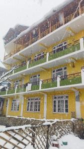 um edifício amarelo com neve caindo sobre ele em The Homstel Manali em Manali