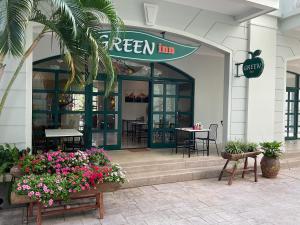 a green inn restaurant with flowers in front of it at Green Inn Phu Quoc Hotel in Phú Quốc
