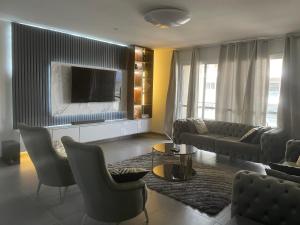 3 bdrm Cityview Apt with Pool, Gym & Children Playground في آكرا: غرفة معيشة مع أريكة وتلفزيون