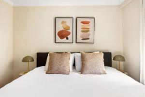 1 dormitorio con 1 cama blanca y 2 cuadros en la pared en Nolita 2BR w Elevator Roof nr Little Italy NYC-921, en Nueva York