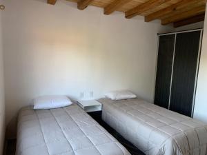 two beds in a room with white walls and wooden ceilings at Vultur in San Rafael +33 photos