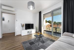 Una sala de estar con un sofá y un televisor en Apartment Filip Premium, en Vrsar