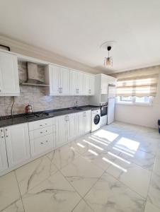 uma cozinha com armários brancos e piso em azulejo em kayan apart em Trabzon