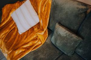 a blanket on a couch with a pillow on it at Le Bertrand • Le Raffinement en Cœur de Ville in Châteauroux