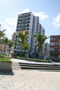 een groot gebouw met palmbomen ervoor bij Apartamento Praia Grande Frente Mar in Praia Grande