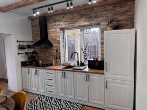 uma cozinha com armários brancos e uma parede de tijolos em FRIENDS HOUSE - Ізки 33 em Nizhniy Studenyy