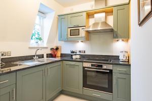una cocina con armarios verdes y fregadero en The Linen House by Bloom Stays, en Canterbury