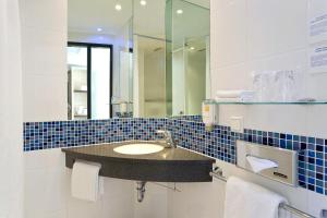 La salle de bains est pourvue d'un lavabo et d'un miroir. dans l'établissement Holiday Inn Express Singen, an IHG Hotel, à Singen