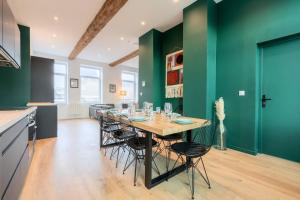 a kitchen with green walls and a table with chairs at Spacious house 11 bedrooms 8 bathrooms 22 people. in Roubaix