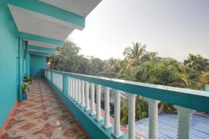a balcony with a view of the ocean and palm trees at Comfort Holiday Home in Baga