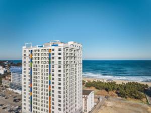 an aerial view of a tall white building next to the ocean at Le Bleu Naksan by Chestertons in Yangyang